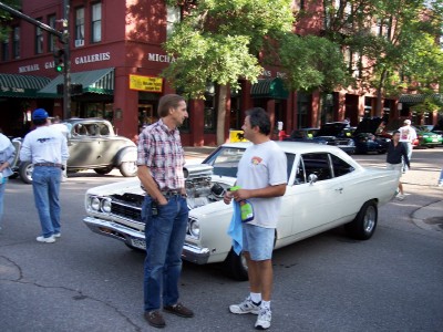 1972 Ford Ranchero - Two men converse next to a white 1969 Plymouth Road Runner with its hood open, revealing a large engine.
