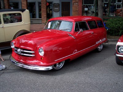 1972 Ford Ranchero - A bright red station wagon with distinctive chrome detailing is parked on a street, with another vehicle visible to its right.