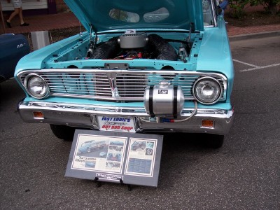 1972 Ford Ranchero - A display board with photos and text is placed in front of a classic turquoise Ford Falcon at a car show.