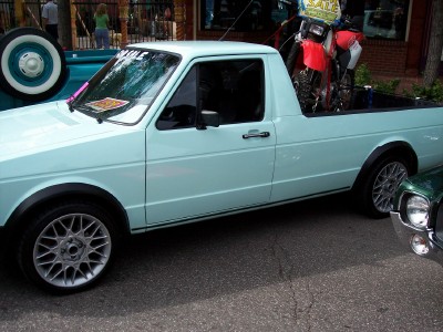 1972 Ford Ranchero - Light blue pickup truck with motorcycle in bed, parked next to another vehicle.