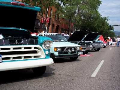 1972 Ford Ranchero - A line of vehicles are parked on a street, with their hoods open, suggesting a car show or event.