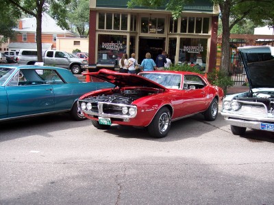 1972 Ford Ranchero - Three cars parked on a street in front of a building with people walking by.