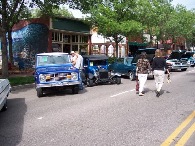 1972 Ford Ranchero - Several vintage vehicles are parked along a street, with people milling around.