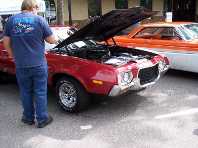 1972 Ford Ranchero - A red 1972 Ford Ranchero is displayed with its hood open, parked next to an orange and white vehicle.