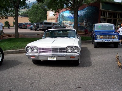 1972 Ford Ranchero - A white 1964 Chevrolet Impala is parked in front of a building with a mural, with a blue Ford Bronco behind it.