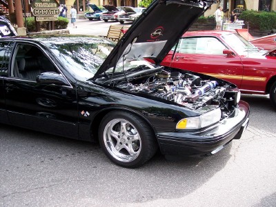 1972 Ford Ranchero - A black sedan is parked with its hood open, revealing the engine compartment.