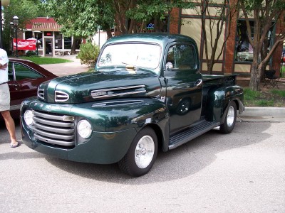 1972 Ford Ranchero - A classic green pickup truck is parked on a street with trees and buildings in the background.