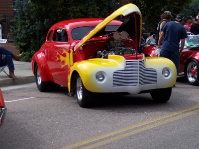 1972 Ford Ranchero - A custom hot rod with a bright red body, yellow accents, and flame decals is displayed with its hood open.