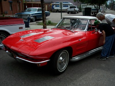 1972 Ford Ranchero - A red 1963 Corvette convertible is admired by two people, with other vehicles in the background.