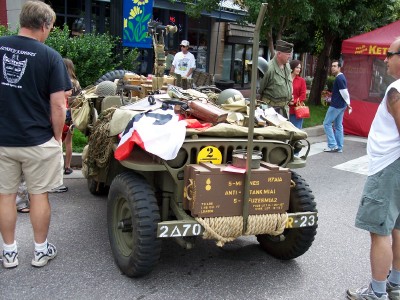 1972 Ford Ranchero - A vintage military jeep is displayed with various equipment and license plates, attracting onlookers.