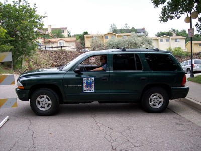 1972 Ford Ranchero - A dark green police SUV is parked on the side of a street, with a police emblem visible on the driver's side door.