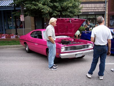 1972 Ford Ranchero - A pink 1973 Dodge Dart Sport is displayed with its hood open, attracting attention from onlookers.
