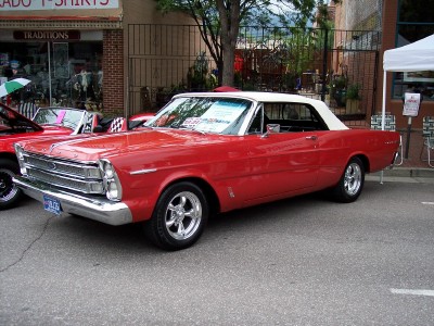 1972 Ford Ranchero - A red convertible with a white top is parked on a street next to another vehicle.