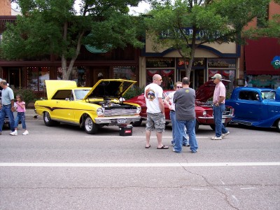 1972 Ford Ranchero - Several classic cars are on display on a street, with people gathered around.