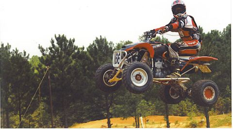 1992 Ford Mustang - A motocross rider soars through the air on an ATV during a race.