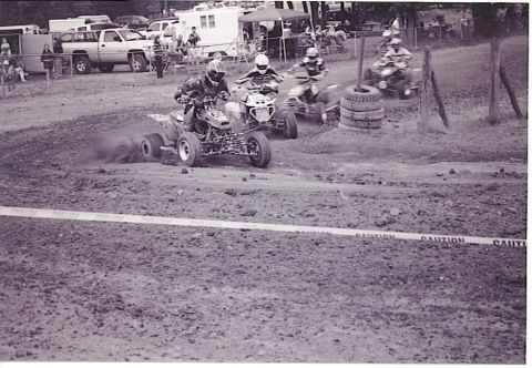 1992 Ford Mustang - Multiple ATVs compete on a muddy track, with spectators and tents in the background.