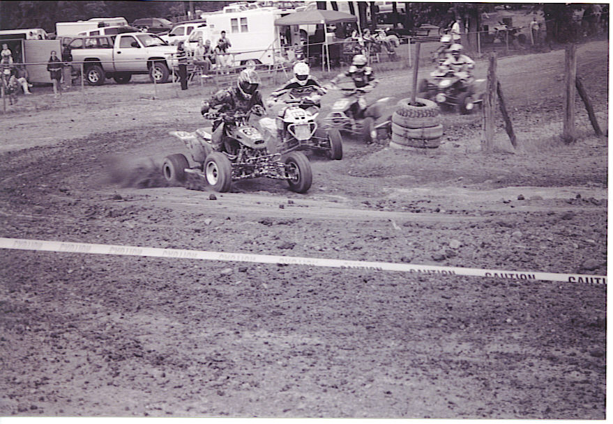 Quads racing on a dirt track, kicking up dust