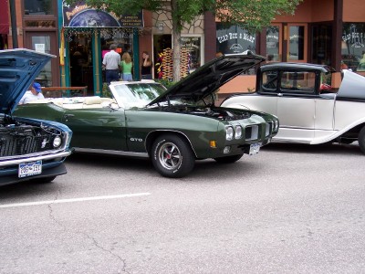1972 Ford Ranchero - Three classic vehicles parked on a street, two with hoods open.