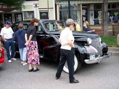 1972 Ford Ranchero - A classic black sedan with whitewall tires is displayed on a street, with onlookers observing.