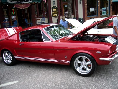 1972 Ford Ranchero - A bright red 1965 Ford Mustang fastback is displayed with its hood open, parked on a street.