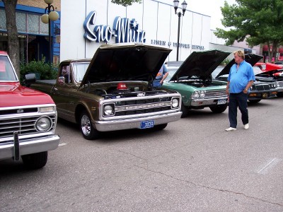 1972 Ford Ranchero - Several classic pickup trucks are displayed with their hoods open in front of a building.