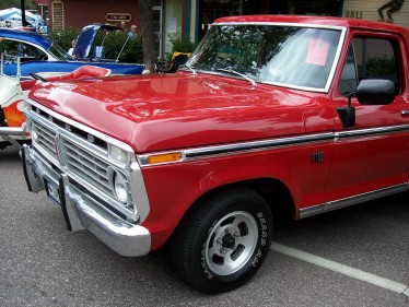 1972 Ford Ranchero - A red pickup truck is parked on a street, with another vehicle visible behind it. The grille suggests a 1973 model year.