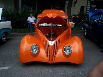 1972 Ford Ranchero - An orange hot rod truck is parked on a street with its hood open.