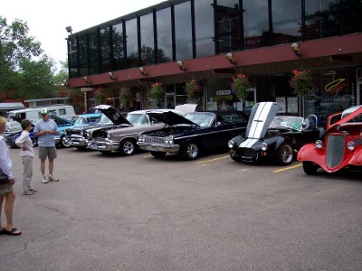 1972 Ford Ranchero - A variety of vintage automobiles are on display in a parking lot, with onlookers observing.