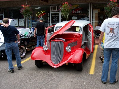 1972 Ford Ranchero - A red hot rod with its hood and doors open is parked next to another car.