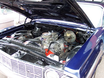 1972 Ford Ranchero - Engine bay of a blue 1964 Chevrolet Impala, a V8 engine with dual carburetors and chrome accents.