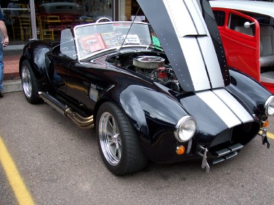 1972 Ford Ranchero - Black AC Cobra replica with hood open, parked outdoors.