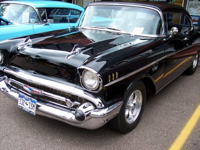 1972 Ford Ranchero - A shiny black 1957 Chevrolet Bel Air is parked next to a blue car.