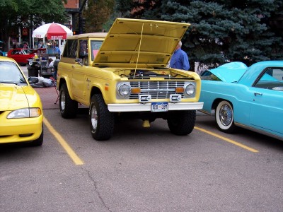 1972 Ford Ranchero - A yellow SUV is parked with its hood open, revealing the engine compartment.