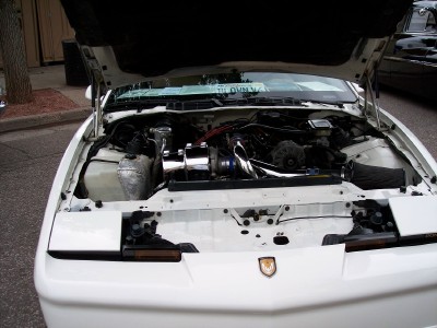 1972 Ford Ranchero - The engine bay of a white car is displayed with the hood fully open, revealing the engine components.