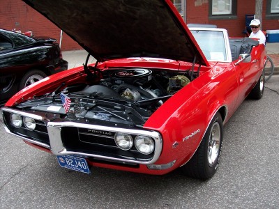 1972 Ford Ranchero - A red convertible's hood is open, revealing the engine bay and a chrome grille with dual headlights.