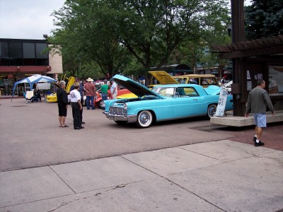 1972 Ford Ranchero - A light blue 1965 Cadillac Sedan de Ville is displayed with its hood open at an outdoor event.