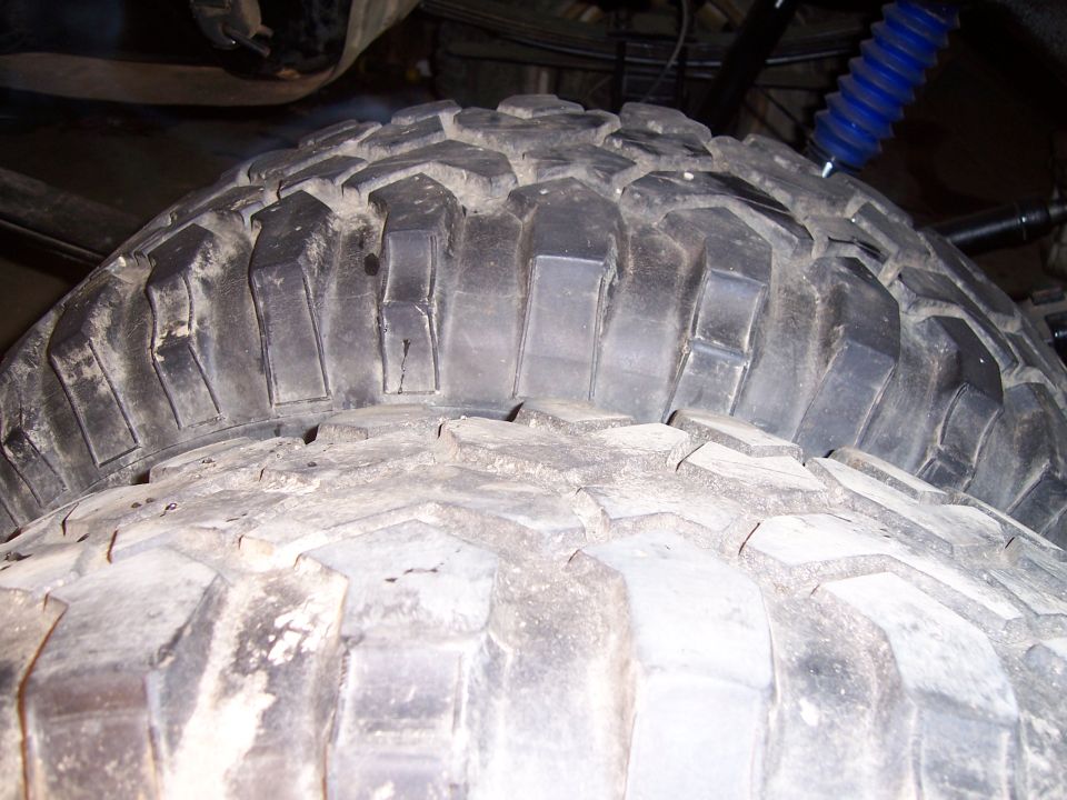 Two large off-road tires stacked, showing aggressive tread pattern