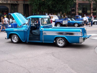 1972 Ford Ranchero - A blue pickup truck is parked on a street with its hood and door open.
