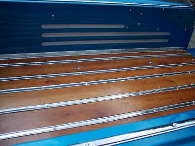 1972 Ford Ranchero - The bed of a blue pickup truck features a custom wood plank floor with polished metal trim.