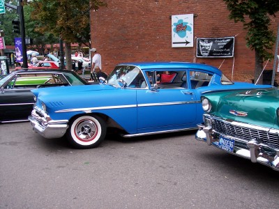 1972 Ford Ranchero - Two vintage Chevrolet sedans, a blue 1958 Impala and a green 1956 model, are parked on a city street.