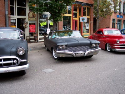1972 Ford Ranchero - Several classic cars are parked along a street in front of shops.