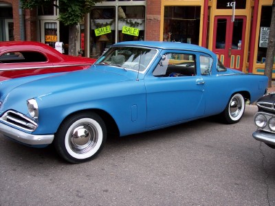 1972 Ford Ranchero - Blue Studebaker coupe parked on street with other vehicles nearby.