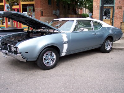 1972 Ford Ranchero - This 1969 Oldsmobile 442 coupe, with its hood open, is parked on a street with buildings in the background.
