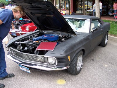 1972 Ford Ranchero - A man inspects the engine of a dark gray coupe, possibly a 1970 model, at an outdoor event.