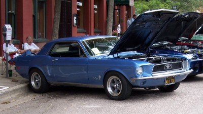 1972 Ford Ranchero - Blue 1967 Ford Mustang coupe with hood open, parked on street. Another vehicle is visible behind it.