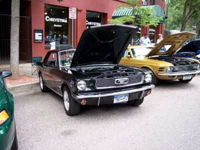 1972 Ford Ranchero - Black 1965 Ford Mustang and yellow 1969 Ford Mustang parked on street with hoods open.