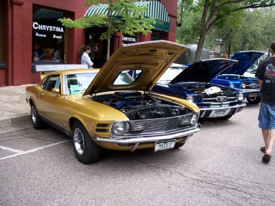 1972 Ford Ranchero - A gold 1970 Ford Mustang Mach 1 is displayed with its hood open, alongside other vehicles.