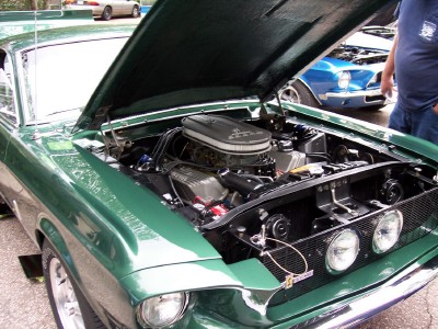 1972 Ford Ranchero - Engine bay of a green 1967 Ford Mustang Fastback, with another vehicle visible behind it.