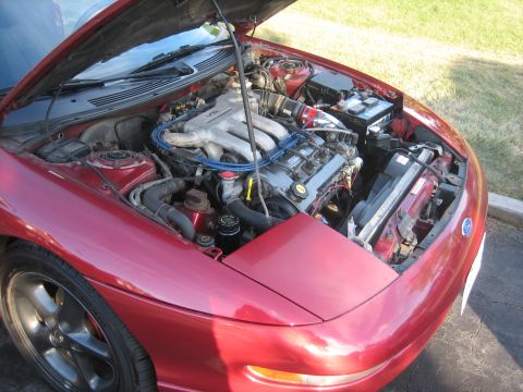 1993 Ford Probe - The V6 engine of a red 1993 Ford Probe is visible with the hood open.