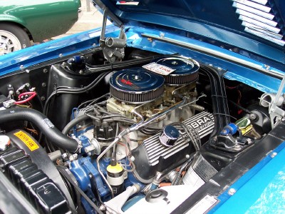 1972 Ford Ranchero - Engine bay details of a blue vehicle, Cobra valve covers and dual carburetors. Another vehicle is partially visible in the background.